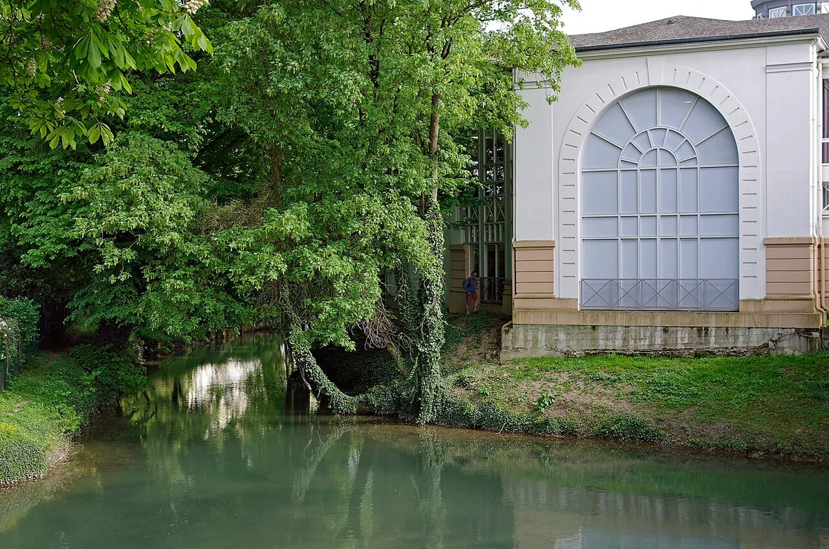 Un bâtiment au bord de l’eau, sous les arbres, à Châlons-en-Champagne.