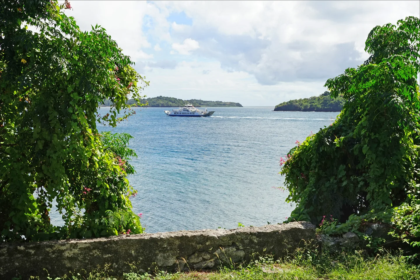Une barge sur le lagon au nord de Dzaoudzi, vue entre les arbres depuis Petite-Terre à Mayotte.