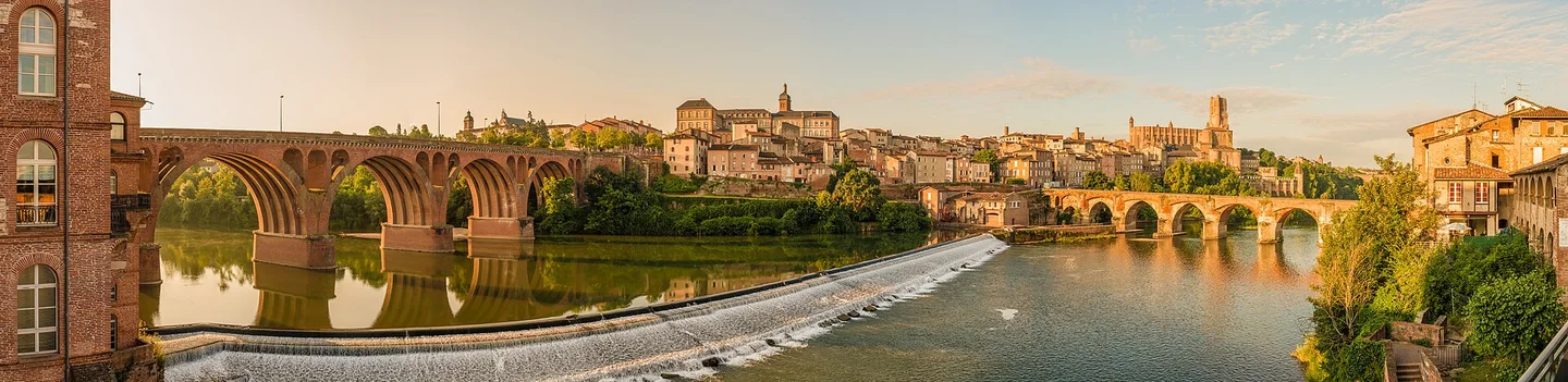Panorama d’Albi au matin : le Tarn, les ponts, les façades de la vieille ville et la cathédrale Sainte-Cécile.