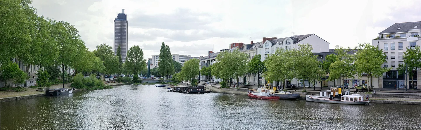 Vue panoramique de l’Erdre à Nantes avec les quais arborés, des bateaux et les immeubles riverains.