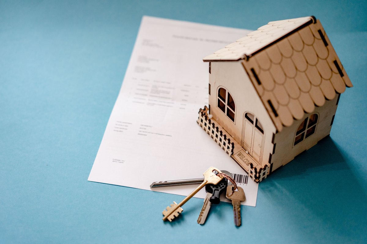 Maquette de maison en bois, clés et documents sur une table, photographie illustrative de la préparation d’une vente.
