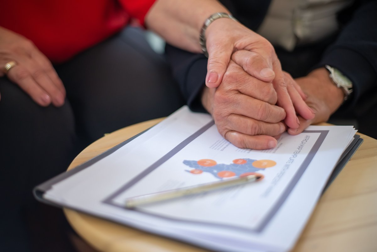 Deux personnes se tiennent les mains au-dessus de documents, photographie illustrative des échanges familiaux.