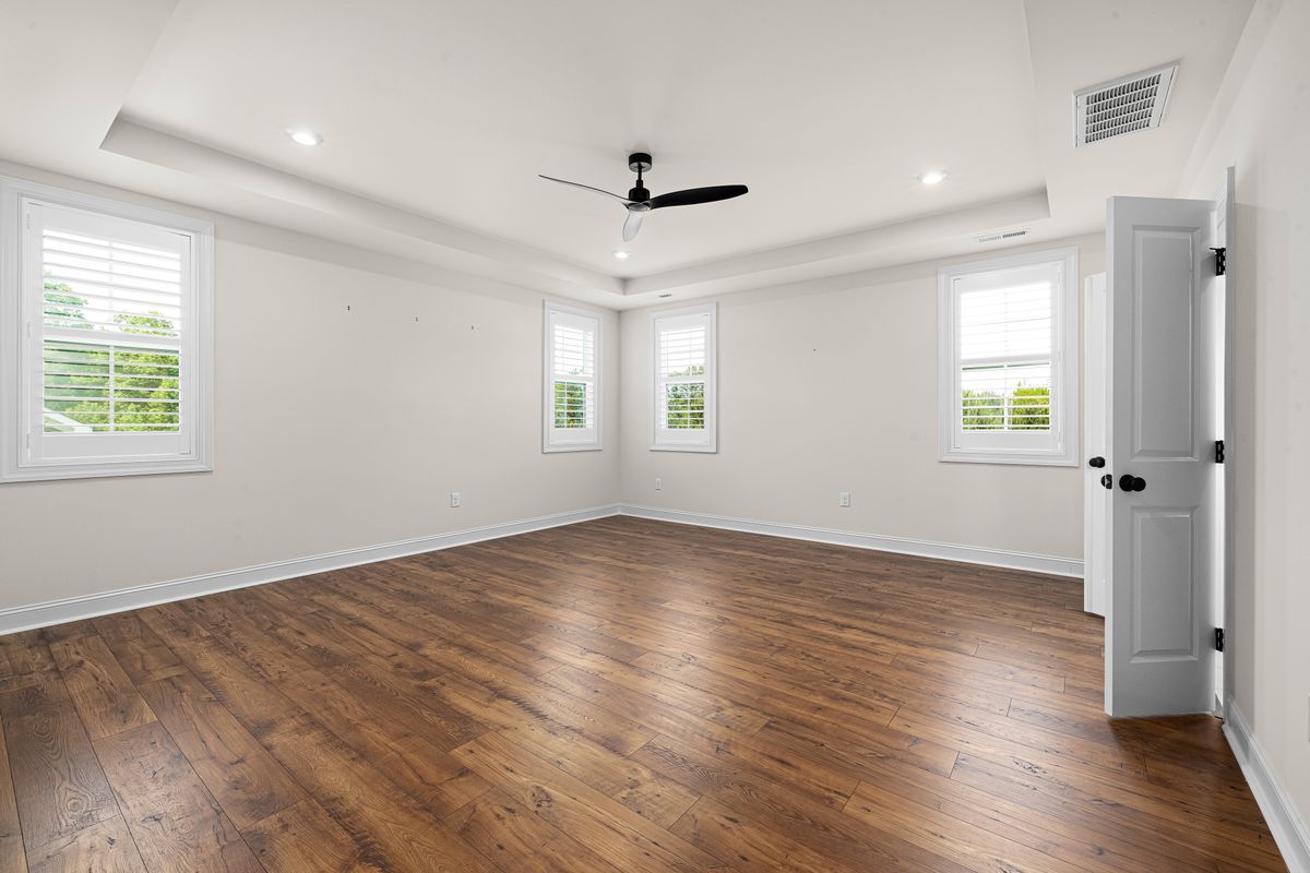 Pièce vide non meublée avec fenêtres et parquet ; photographie illustrative.