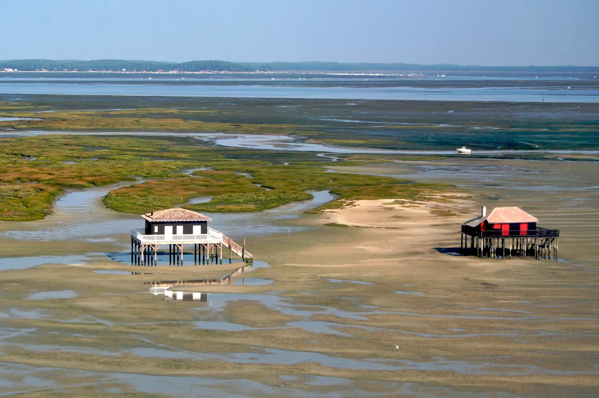 Deux cabanes tchanquées sur pilotis et les bancs découverts à marée basse près de l’île aux Oiseaux, dans le bassin d’Arcachon.